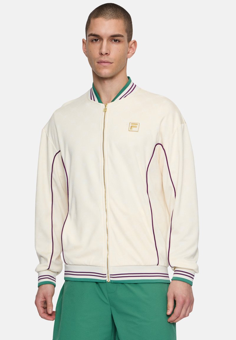 Krämsfärgad zip-up jacka med lila och gröna randiga ribbade kragar och manschetter. Har en subtil logotyp och sidopipingdetaljer. Mjuk textur.