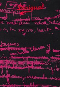 Tessuto nero con testo e linee simili a scritte rosa a mano. Il nome del marchio "Desigual" è ricamato in rosso, in evidenza.
