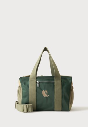 Sac polochon vert et beige avec poche zippée sur le devant, logo beige, deux poignées et bandoulière ajustable sur fond clair.