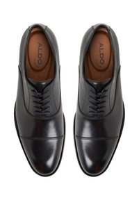 Scarpe da uomo in pelle nera con finitura liscia, design con lacci e punta leggermente appuntita. L'interno presenta un marchio di colore marrone.