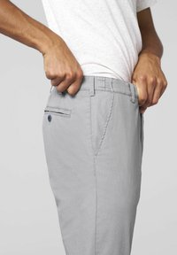 Lichtgrijze broeken van een gestructureerde stof, met een platte voorkant, zijzakken en een achterzak met een knoopsluiting.