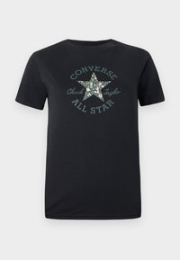 Camiseta de algodón negra con una estrella verde estampada con flores y el texto "Converse Chuck Taylor All Star" en un diseño circular. Mangas cortas.
