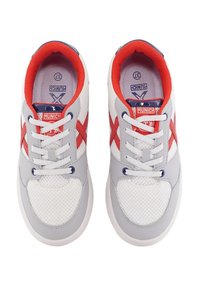 Zapatillas de malla blancas con acentos grises, detalles en rojo y azul, cordones en la parte frontal y una suela texturizada. Marca en la lengüeta y en el lateral.