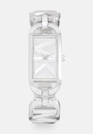 Reloj rectangular plateado con una correa texturizada transparente, que cuenta con una esfera blanca y marcadores y manecillas de hora minimalistas. Acentos de hardware metálico.