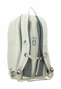 Mochila gris claro con respaldo de malla, correas acolchadas y hebillas ajustables. Presenta detalles del logo y canales de aire prominentes para ventilación.