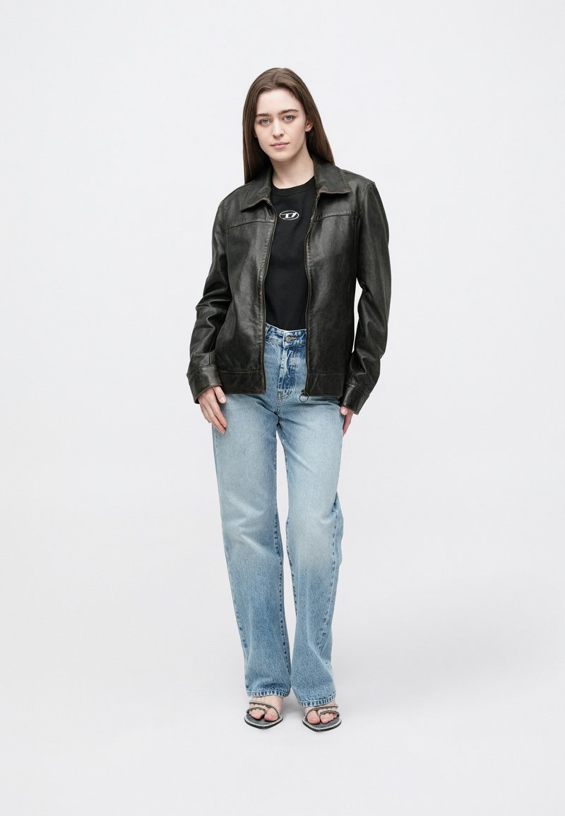 Black leather jacket with a collared design, paired with a fitted black top and light blue frayed jeans. Worn sandals with a patterned sole.