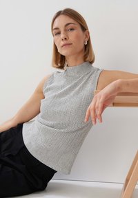 Mouwloze top in een zwart-wit geruit patroon, met een hoge halsontwerp en textiel stof, gecombineerd met zwarte broek.