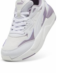 Baskets Puma blanches et violet clair avec tige en mesh et cuir, lacets blancs et semelle épaisse sculptée, inclinées pour montrer les détails avant et latéraux.