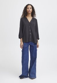 Black synthetic long-sleeve blouse with a V-neck and buttons, paired with wide-leg blue denim pants featuring side pockets and a faded wash.