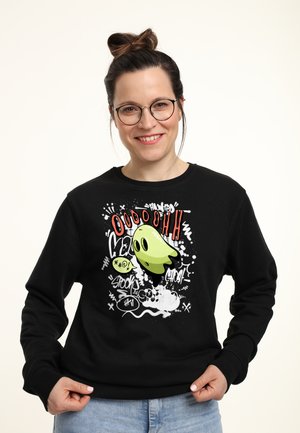 Schwarzer Pullover mit einem Cartoon-Geistergrafik in Grün, rotem Text und weißen Spritzern. Das Design enthält verspielte Gesichtsausdrücke.