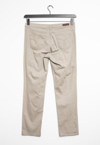 Beige cotton pants hanging on a black hanger, featuring two back pockets with curved stitching and a straight-leg design.