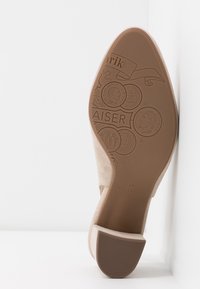 Semelle de chaussure pour femmes en daim beige avec des motifs en relief, des motifs circulaires et la marque "Peter Kaiser" ; matériau en caoutchouc lisse marron.
