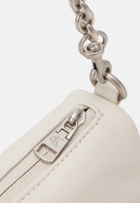 Borsa in pelle bianca con zip argentata dotata di tirazip brandizzato e tracolla in catena metallica, caratterizzata da una superficie liscia e un design minimalista.