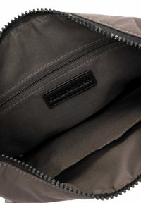 Bolsa de tela gris con cierre de cremallera, que cuenta con una etiqueta de cuero negro y un interior suave. Borde texturizado y múltiples compartimentos internos.