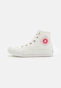 Zapatilla alta de lona blanca con un colorido bordado floral en el costado, ojales de metal y suela de goma texturizada.