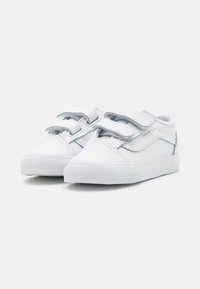 Baskets blanches en toile avec deux sangles Velcro, bout rond, semelle en caoutchouc texturée et accents gris subtils sur le côté.