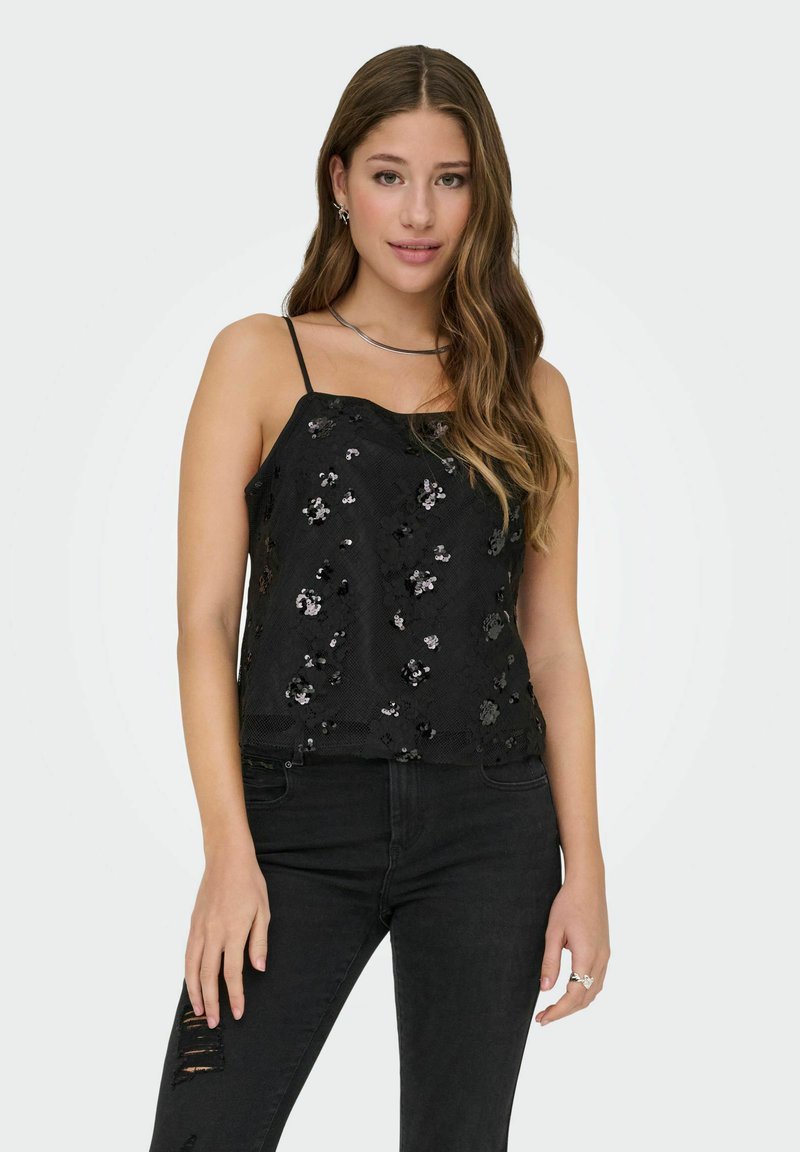 Czarny bezrękawnik z delikatnym kwiatowym wzorem z cekinów, teksturowaną tkaniną i cienkimi ramiączkami, w połączeniu z podartymi czarnymi dżinsami.