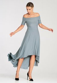 Sukienka opadająca z ramion w kolorze szarym z falującym asymetrycznym dołem, wykonana z lekkiego materiału, z krótkimi rękawami i dopasowanym gorsetem.