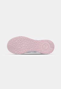 Semelle d'une chaussure en caoutchouc rose clair avec motifs circulaires antidérapants et logo Puma près du talon sur fond blanc uni.