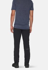 Svarta softshell-byxor med artikulerade knän och en åtsittande design. Kombineras med en mörkblå kortärmad skjorta i strukturerat tyg.