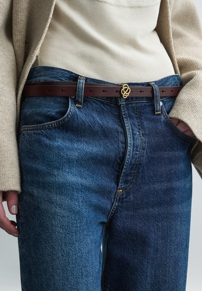 Μπλε τζιν παντελόνι με εφαρμοστή μέση, διακοσμημένο με αντίθετες ραφές, εμπρόσθιες τσέπες και καφέ δερμάτινη ζώνη με χρυσή αγκράφα.