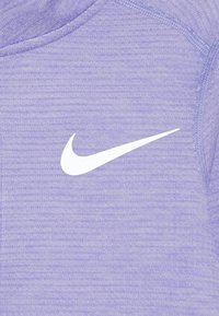 Lila Sportstoff mit einem strukturierten Muster, das in der Mitte ein auffälliges weißes Nike-Swoosh-Logo zeigt.