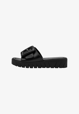 Black faux leather slide sandal with a wide strap featuring a rectangular buckle. Thick, textured sole with a zigzag pattern.