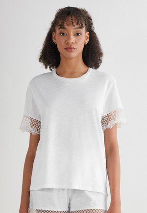 Witte t-shirt met korte mouwen, voorzien van ingewikkelde kantafwerking. Zachte stof, ronde halslijn en een losse pasvorm.