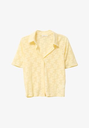 Bluzka z krótkim rękawem w kolorze żółtym z wzorem kwiatowym, z zapięciem na guziki i miękką fakturą. Posiada klasyczny kołnierzyk i luźny krój.