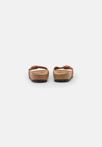 Sandalias de corcho marrones con dos correas ajustables. Material ligero y suela de goma texturizada que proporcionan comodidad y estabilidad.