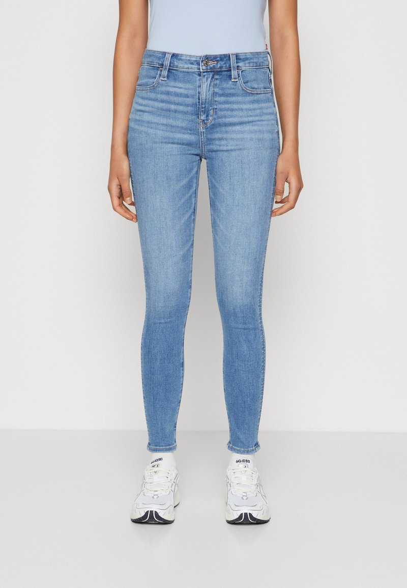 Lys blå skinny jeans i denim, med midjehøyde, fem lommer og en glatt tekstur. Nederkantene er frynset ved anklene.