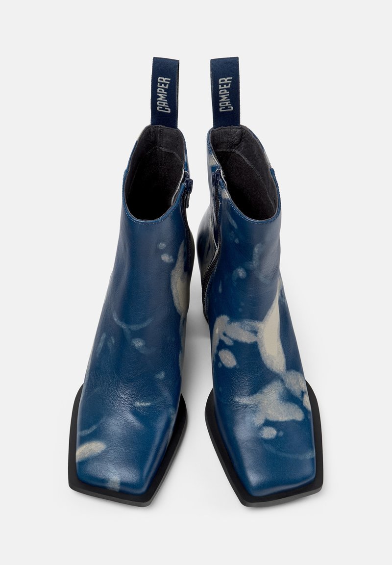 Blå läderankleboots med en glänsande yta, med fyrkantig tå, dragkedjestängning och lätta abstrakta mönster.