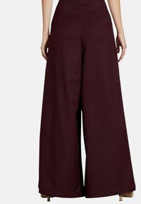 Wijdlopende broek in diep bordeaux stof, met een hoge taille en strakke lijnen. De achterkant toont minimale stiksels en een gladde textuur.