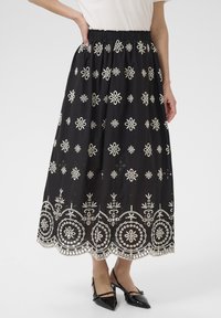 Zwarte rok met witte bloemige borduursels en een scalloped zoom. Gemaakt van lichtgewicht stof met een elastische tailleband voor comfort.
