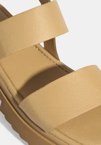 Braune Leder-Sandalen mit zwei breiten Riemen, einer strukturierten Fußbett und einer dicken, konturierten Sohle. Das Design ist offen und lässig.