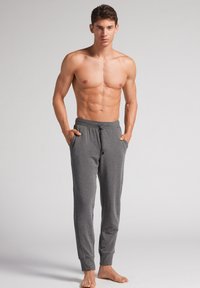 Grijze joggers met een trekkoord in de taille, zijzakken en aangesloten enkels. Gemaakt van zacht, lichtgewicht materiaal.