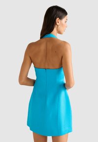 O rochie cu gât halter, de culoare turcoaz strălucitor, cu un design ajustat și un fermoar ascuns la spate. Material neted și ușor.
