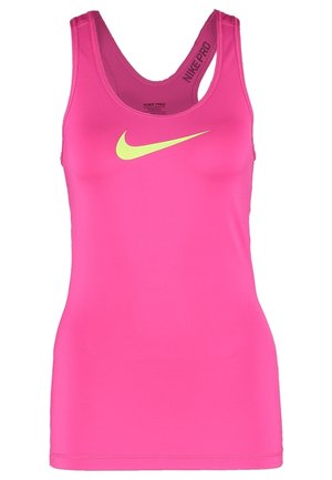 Femme debout, portant un débardeur rose Nike, un short jaune fluo Nike et des chaussures de course Nike jaune fluo et blanches.