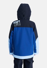 Niebieska i czarna kurtka śniegowa z kapturem; posiada logo na górnej części pleców, jasnoniebieskie akcenty i gładką teksturę.