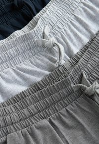 Tre par shorts med elastisk midja i navy, grå och ljusgrå. Varje par har en dragsko och ribbad textur vid midjan.
