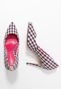 Des escarpins à bout pointu avec un motif pied-de-poule dans les tons noir, blanc et violet. Présentent un intérieur rose et un talon aiguille fin.