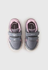 Gray and pink sneakers with a textured upper, double Velcro straps, and patterned soles. Branding visible on the side and insole.