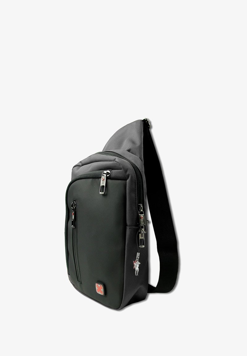 Compact zwarte schoudertas met meerdere ritscompartimenten, verstelbare schouderband en een rood kruislogo op het voorvak.