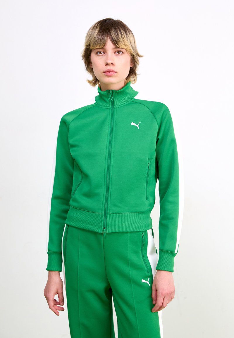Green zip-up track jacket with ribbed collar, featuring white stripes along sleeves. Logo embroidered on chest, made of smooth athletic fabric.