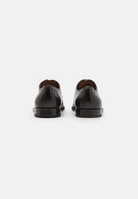 Chaussures en cuir noir au fini lisse, à bout rond et à petit talon. Pas de matériel visible ni d'accent supplémentaire.