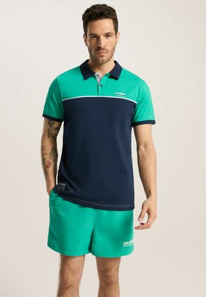 Męska koszulka polo w kolorze teal i granatowym z zapięciem na guziki, krótkimi rękawami i białymi paskami. Połączona z pasującymi zielonymi szortami.