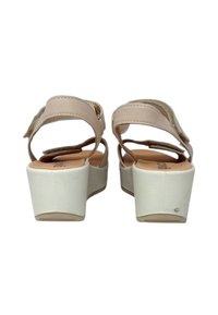 Sandali platform beige con cinturino alla caviglia. Parte superiore in finta pelle liscia, dettagli testurizzati e tacco chunky bianco. Design aperto sul retro.