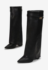 Bottes noires en cuir montantes avec un bout pointu, fermeture à glissière et une sangle accentuée par un détail en métal doré. Design à talon plat.