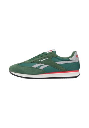 Zapatilla verde de Reebok con detalles en blanco y gris, acento rojo sobre la suela blanca, cierre de cordones en la parte delantera y logo de Reebok en el lateral y el talón.
