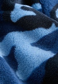 Fleecedeken met een gestructureerd oppervlak in blauwtinten en zwart, met een abstract camouflagedesign en zachte, warme stof.
